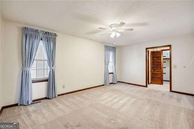 carpeted empty room with ceiling fan and a textured ceiling