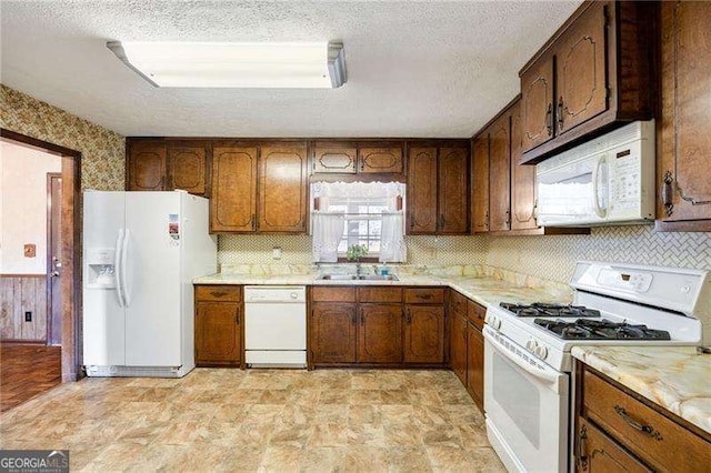 kitchen featuring decorative backsplash, white appliances, sink, and a textured ceiling