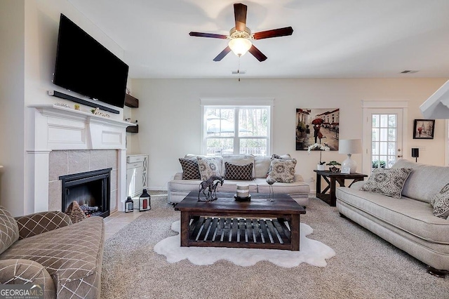 living room featuring a tiled fireplace, a wealth of natural light, and ceiling fan