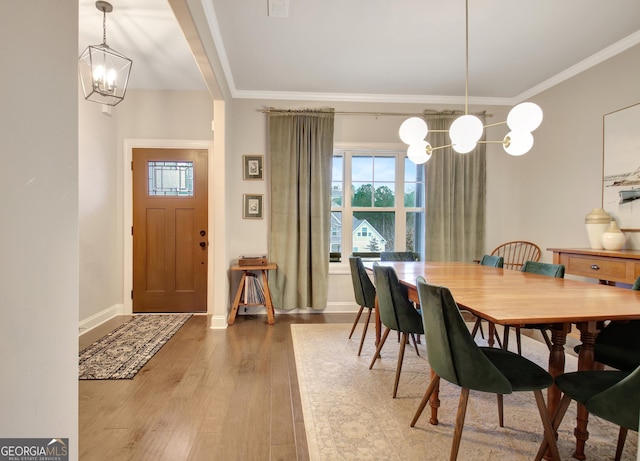 dining room with wood-type flooring, a healthy amount of sunlight, a chandelier, and crown molding