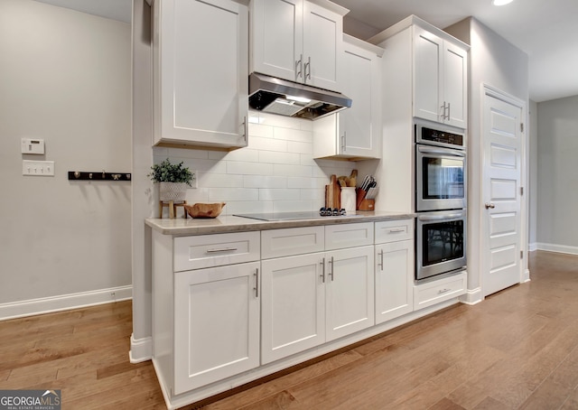 kitchen with double oven, light hardwood / wood-style floors, white cabinets, black electric cooktop, and decorative backsplash