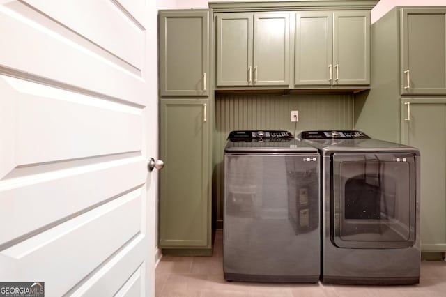 laundry room with washer and dryer, light tile patterned floors, and cabinets