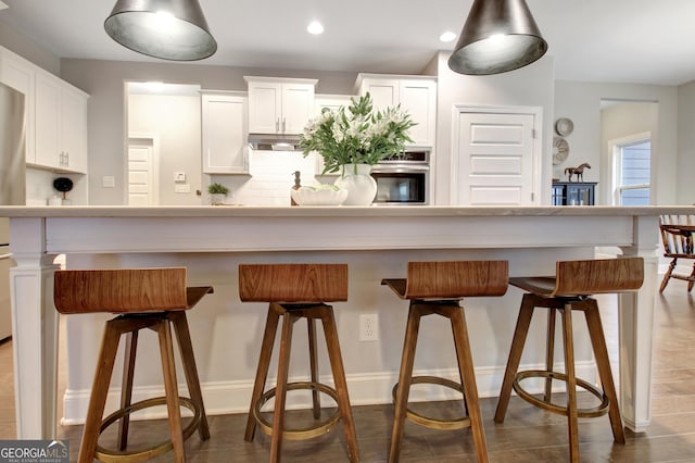 kitchen featuring appliances with stainless steel finishes, a kitchen breakfast bar, a kitchen island, white cabinets, and backsplash