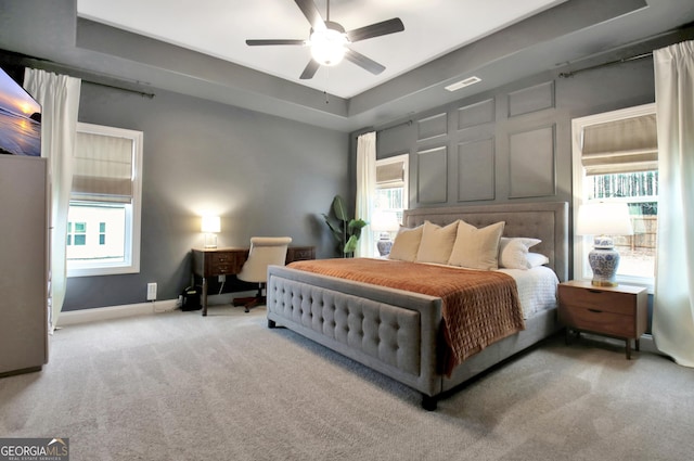 carpeted bedroom with a tray ceiling and ceiling fan