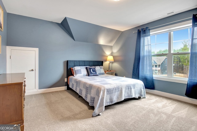 bedroom with vaulted ceiling and light carpet