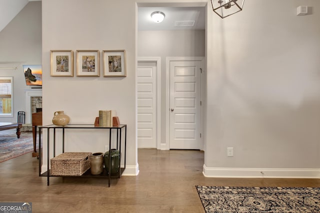 hallway with hardwood / wood-style flooring and vaulted ceiling