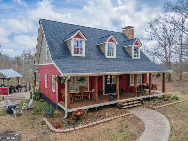 view of front of property with a shingled roof, covered porch, and a chimney