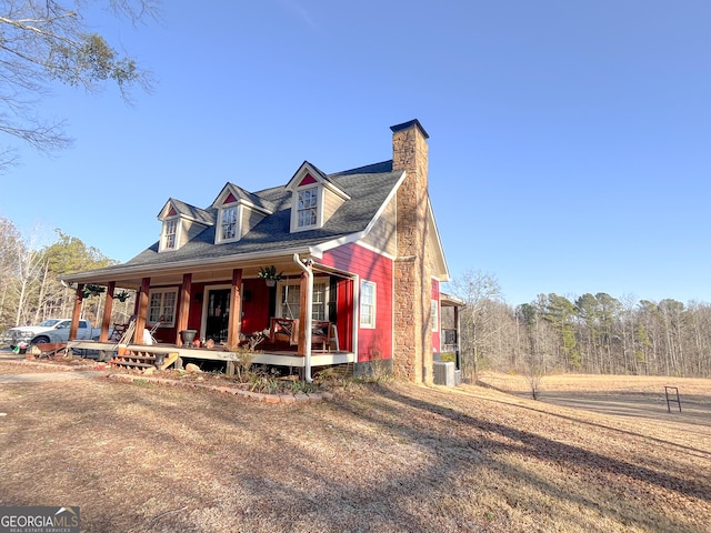 view of front of home featuring cooling unit, covered porch, and a chimney