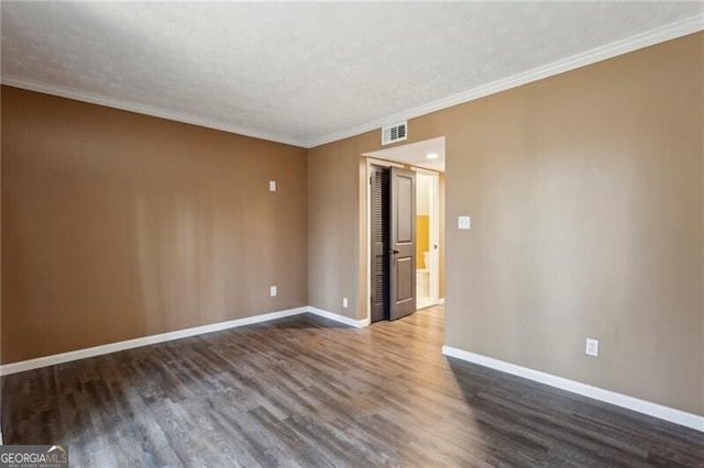 empty room with ornamental molding, dark hardwood / wood-style floors, and a textured ceiling