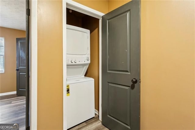 clothes washing area featuring stacked washer and clothes dryer and light wood-type flooring