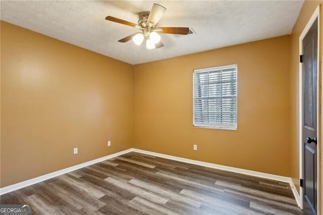 empty room featuring ceiling fan, a textured ceiling, and dark hardwood / wood-style flooring