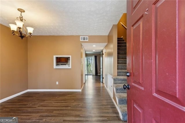 entryway featuring a notable chandelier, dark hardwood / wood-style floors, and a textured ceiling