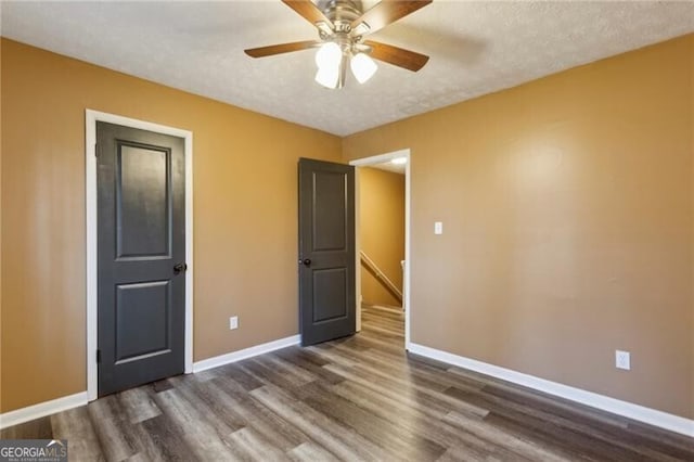 unfurnished bedroom with dark hardwood / wood-style flooring, ceiling fan, and a textured ceiling