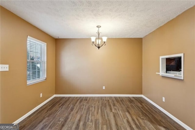 empty room featuring hardwood / wood-style floors, a textured ceiling, and a chandelier