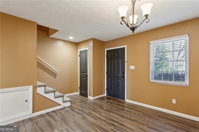 entrance foyer featuring dark hardwood / wood-style flooring, a textured ceiling, and an inviting chandelier