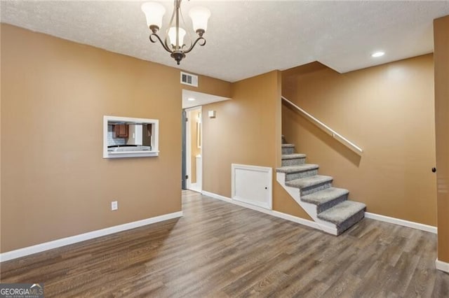 interior space with wood-type flooring, a textured ceiling, and a notable chandelier