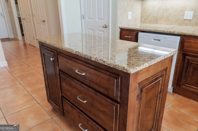 kitchen with backsplash, light tile patterned floors, and light stone countertops