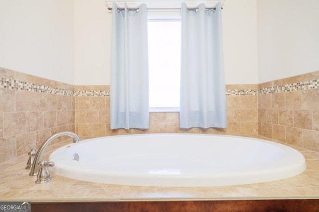 bathroom featuring tiled bath and a healthy amount of sunlight