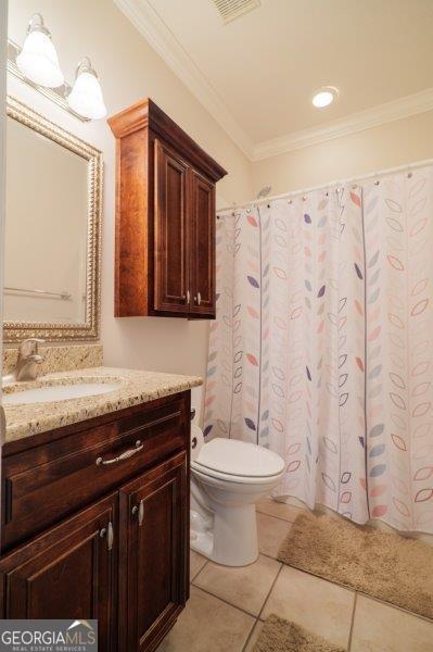 bathroom with crown molding, vanity, toilet, and tile patterned flooring