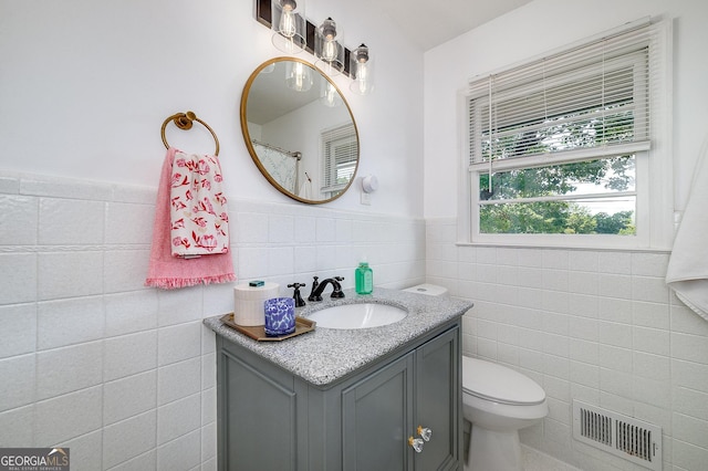 bathroom with tile walls, vanity, and toilet