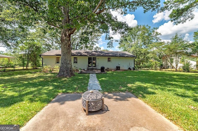 back of house with a yard and a fire pit