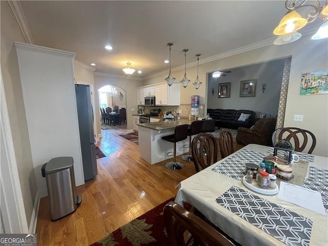 dining space with sink, wood-type flooring, and ornamental molding