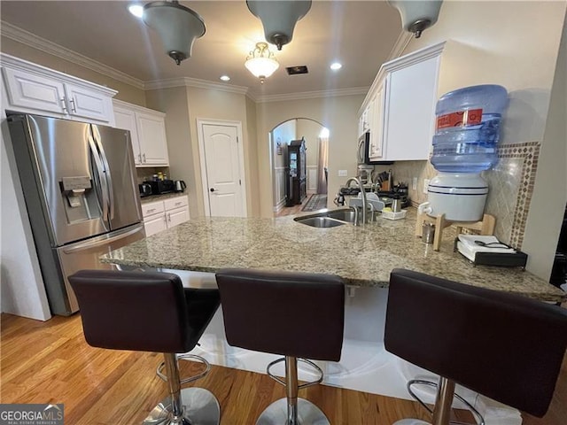 kitchen with appliances with stainless steel finishes, sink, white cabinets, backsplash, and kitchen peninsula