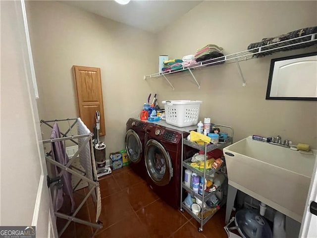 clothes washing area featuring dark tile patterned floors, sink, and washer and clothes dryer