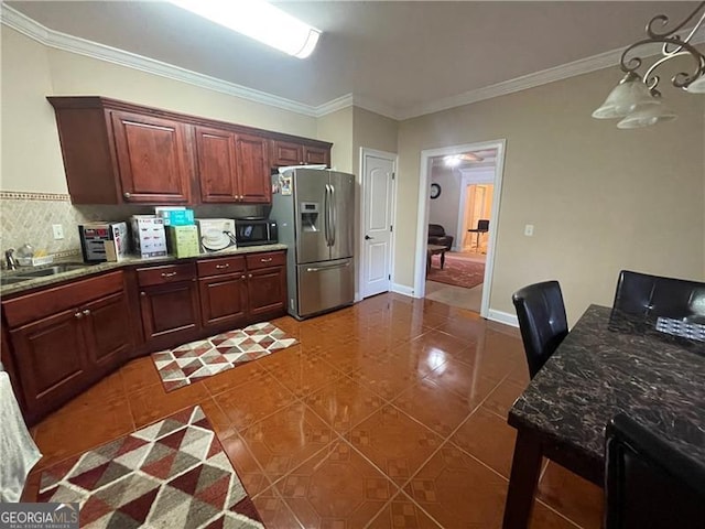 kitchen with sink, dark stone countertops, dark tile patterned flooring, ornamental molding, and stainless steel refrigerator with ice dispenser