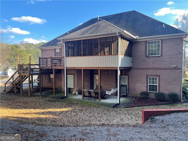 back of property with a sunroom, a deck, and a patio area