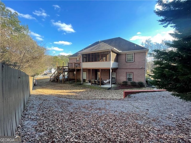 back of property with a deck, a patio area, and a sunroom