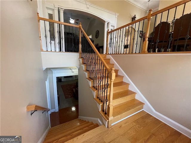 stairway with hardwood / wood-style floors and ceiling fan