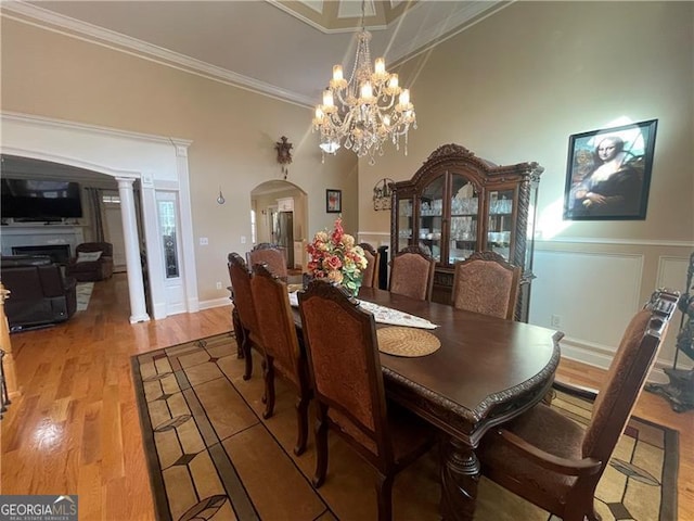 dining room with light hardwood / wood-style flooring, ornamental molding, decorative columns, and a chandelier