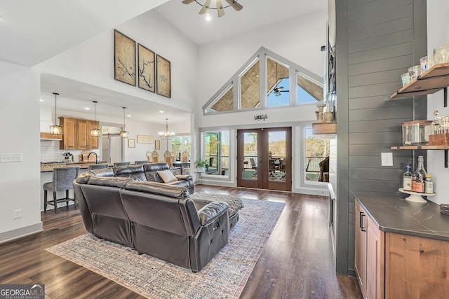 living room featuring a high ceiling, dark hardwood / wood-style floors, ceiling fan with notable chandelier, and french doors