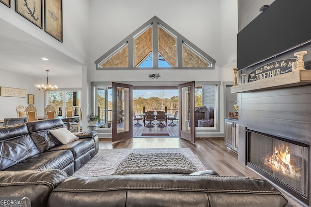 living room featuring hardwood / wood-style flooring, french doors, a chandelier, and a high ceiling