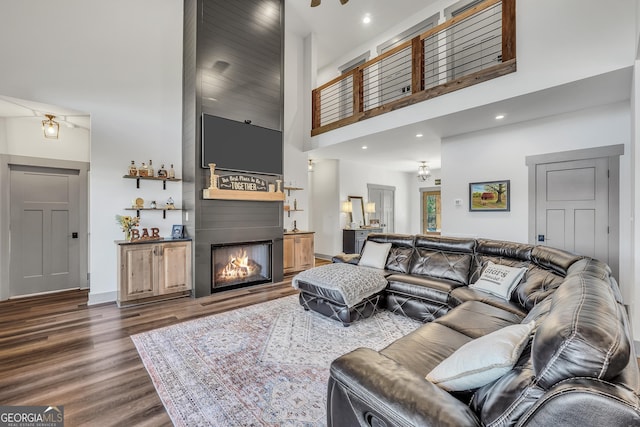 living room featuring a large fireplace, dark hardwood / wood-style floors, and a high ceiling