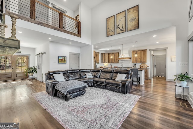 living room with french doors, a towering ceiling, and dark hardwood / wood-style floors