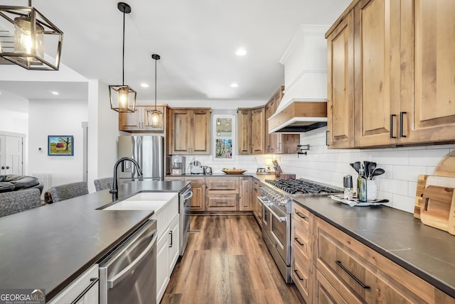 kitchen with appliances with stainless steel finishes, pendant lighting, sink, decorative backsplash, and dark wood-type flooring