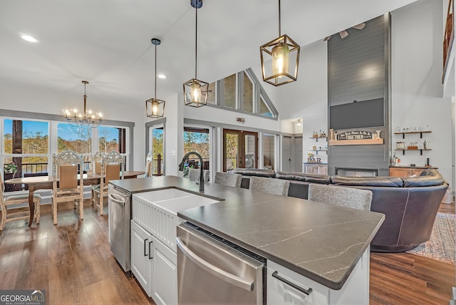 kitchen featuring white cabinetry, a kitchen island with sink, stainless steel dishwasher, and decorative light fixtures