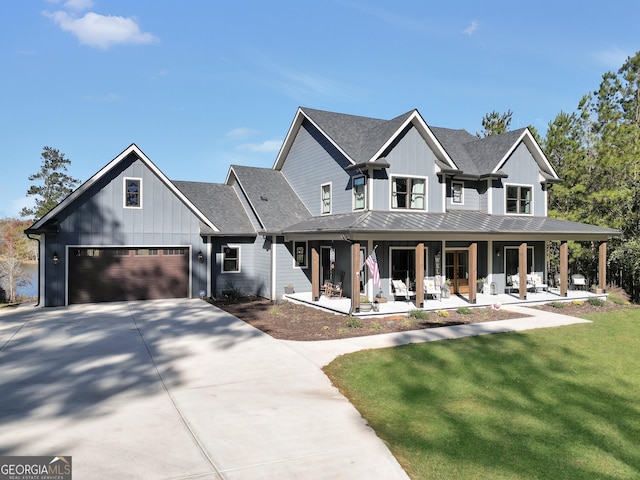 modern inspired farmhouse featuring a garage, covered porch, and a front lawn