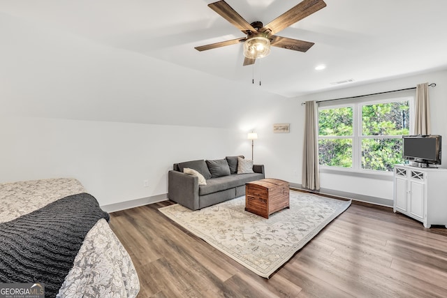 living room with dark hardwood / wood-style flooring, vaulted ceiling, and ceiling fan