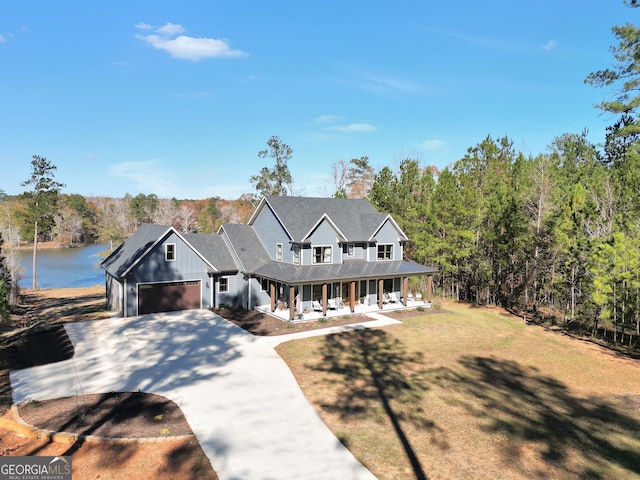 view of front of property with a porch, a garage, a front yard, and a water view