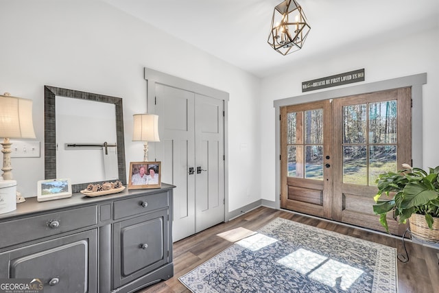 entrance foyer with dark hardwood / wood-style flooring, a notable chandelier, and french doors