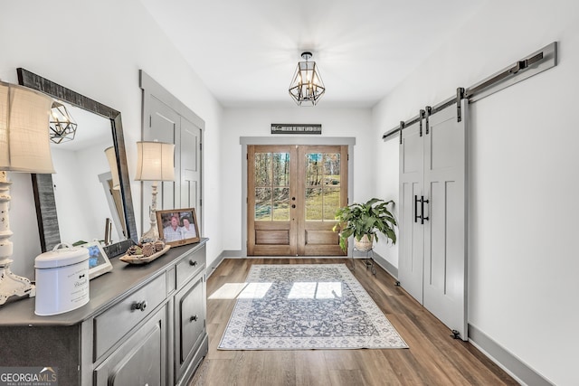 entryway featuring hardwood / wood-style flooring, a barn door, french doors, and a notable chandelier