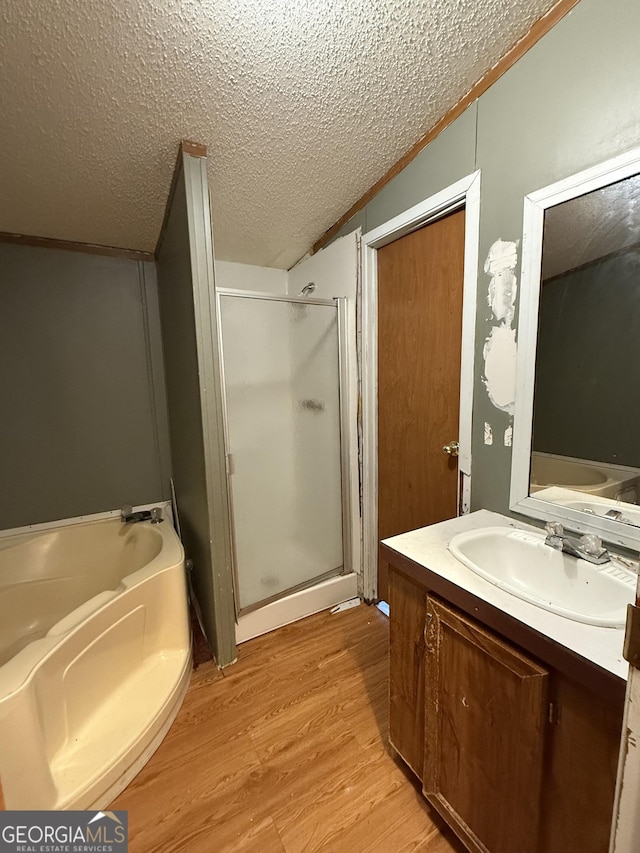 bathroom with separate shower and tub, vaulted ceiling, a textured ceiling, vanity, and hardwood / wood-style floors