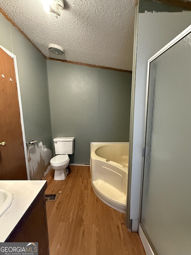 full bathroom with vanity, independent shower and bath, hardwood / wood-style floors, and a textured ceiling