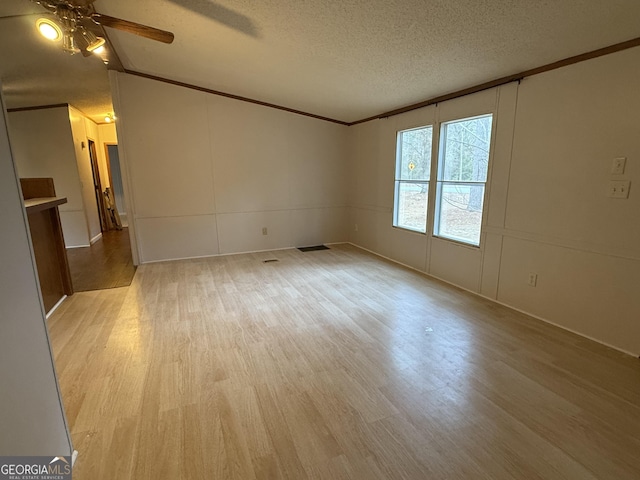 unfurnished room featuring vaulted ceiling, ornamental molding, ceiling fan, a textured ceiling, and light hardwood / wood-style flooring