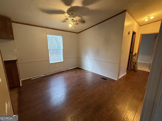 empty room with crown molding, dark hardwood / wood-style floors, a textured ceiling, and ceiling fan