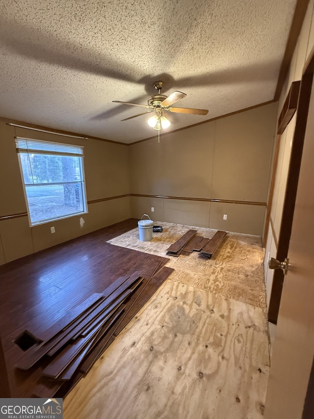 empty room featuring hardwood / wood-style flooring, ceiling fan, crown molding, and a textured ceiling