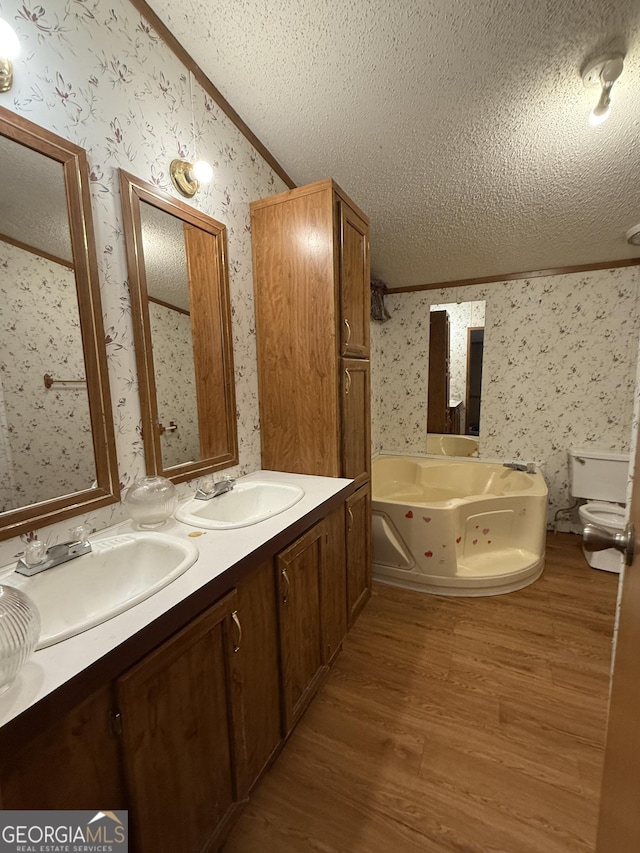 bathroom with toilet, vaulted ceiling, a textured ceiling, a bathtub, and hardwood / wood-style floors